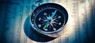 compass laying atop stock section of newspaper